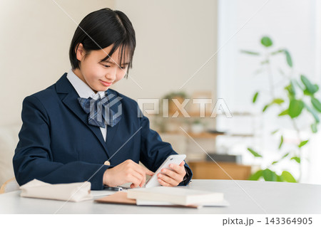 家でスマホを使って勉強,宿題,リビング学習する中学生,高校生,生徒の女の子 143364905