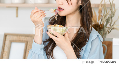 自宅のキッチンでサラダを食べるダイエット中の若いアジア人女性 自宅のキッチンでサラダを食べるダイエット中の若いアジア人女性 143365309