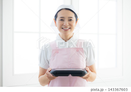 弁当を持つエプロン姿の女性 弁当を持つエプロン姿の女性 143367603