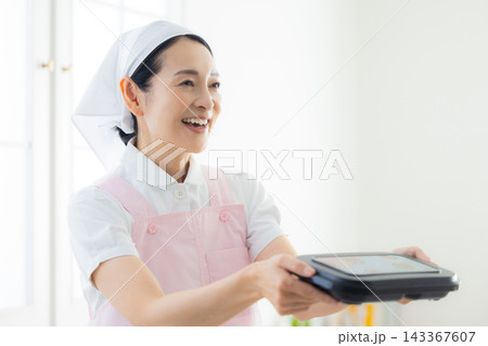 弁当を持つエプロン姿の女性 143367607