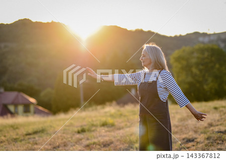 Senior woman practicing meditation outdoors in peaceful countryside. 143367812