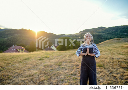 Senior woman practicing meditation outdoors in peaceful countryside. 143367814