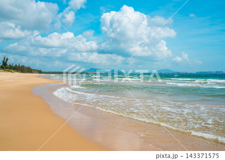 Sanya Hainan travel destination view. Sand beach, ocean waves, and cityscape on the horizon at summer day in Haitang Bay Sanya Hainan travel destination view. Sand beach, ocean waves, and cityscape on the horizon at summer day in Haitang Bay 143371575