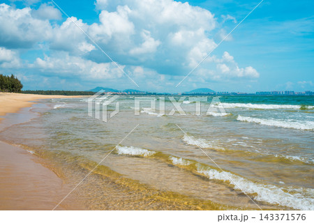 Tropical beach at Haitang Bay in Sanya Hainan with golden sand, ocean waves, and blue sky. Perfect summer vacation destination Tropical beach at Haitang Bay in Sanya Hainan with golden sand, ocean waves, and blue sky. Perfect summer vacation destination 143371576