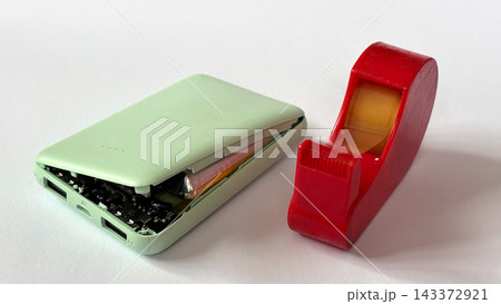 膨張したモバイルバッテリーのUSB端子をテープで塞ぐ安全対策｜白背景 143372921
