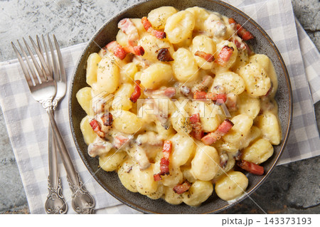 creamy gnocchi carbonara with a rich savory sauce made from eggs, cheese and pancetta closeup on the plate. Horizontal top view 143373193
