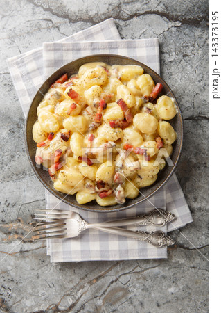 carbonara gnocchi, bathed in a velvety sauce crafted from creamy egg yolks and decadent closeup on the plate. Vertical top view carbonara gnocchi, bathed in a velvety sauce crafted from creamy egg yolks and decadent closeup on the plate. Vertical top view 143373195