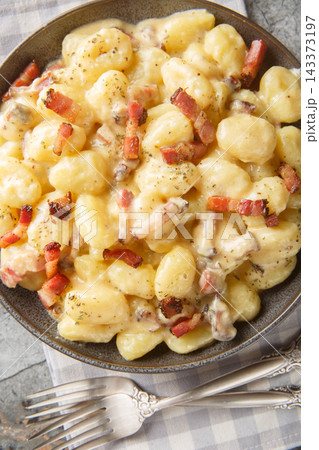 Italian gnocchi carbonara coated in a velvety egg yolk, pancetta and Parmigiano sauce closeup on the plate on the table. Vertical top view 143373197