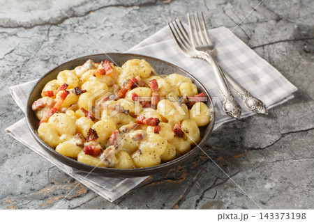 rich and creamy gnocchi carbonara made with homemade pillowy gnocchi and tossed in an easy carbonara sauce with pancetta closeup on the plate. Horizontal 143373198