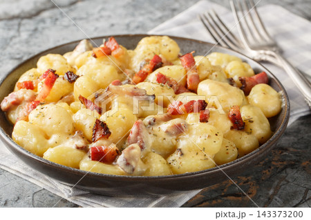 Close-up of potato gnocchi with fried bacon, velvet sauce, and Parmesan in a bowl. Horizontal Close-up of potato gnocchi with fried bacon, velvet sauce, and Parmesan in a bowl. Horizontal 143373200