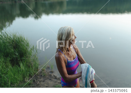Mature woman enjoying healthy outdoor swimming in natural lake. Mature woman enjoying healthy outdoor swimming in natural lake. 143375091