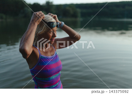 Active woman practicing cold water swimming in lake during autumn. Active woman practicing cold water swimming in lake during autumn. 143375092