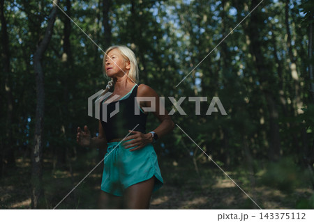 Active senior woman runner jogging in forest. Active senior woman runner jogging in forest. 143375112