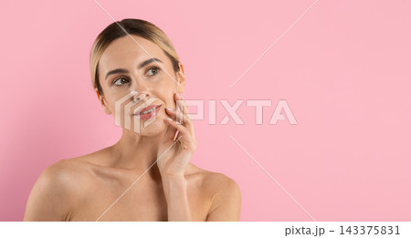 Young woman touching her cheek while looking aside against pink studio background Young woman touching her cheek while looking aside against pink studio background 143375831