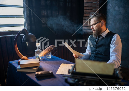 Writer reading a manuscript page at his vintage desk Writer reading a manuscript page at his vintage desk 143376052