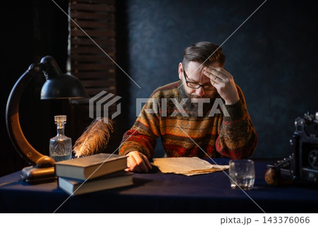 Tired writer holding his forehead at a desk Tired writer holding his forehead at a desk 143376066