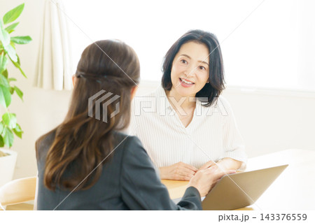 リビングでミドルエイジの女性に話をする日本人のセールスレディ 143376559