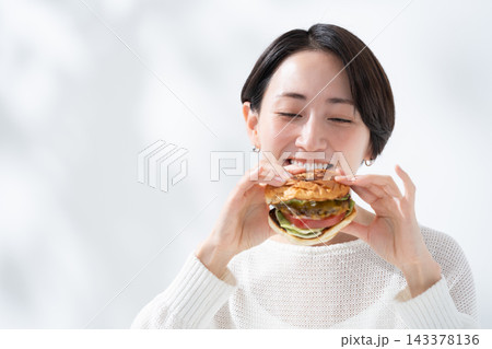 美味しいハンバーガーを食べる笑顔の女性 美味しいハンバーガーを食べる笑顔の女性 143378136