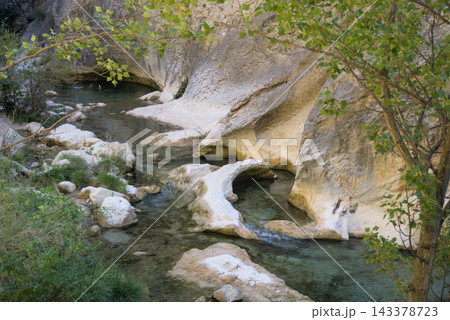 Clear Rio Vero flowing between white polished limestone shapes under poplar branches Clear Rio Vero flowing between white polished limestone shapes under poplar branches 143378723