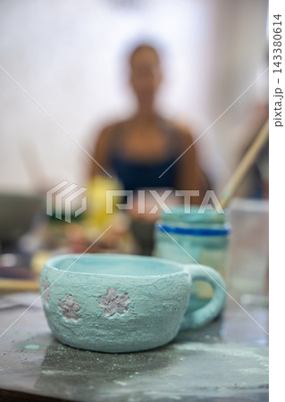 Handmade ceramic mug with floral decoration covered in glaze before kiln firing. Finished pottery piece represents craftsmanship, creativity and artisan ceramic production Handmade ceramic mug with floral decoration covered in glaze before kiln firing. Finished pottery piece represents craftsmanship, creativity and artisan ceramic production 143380614