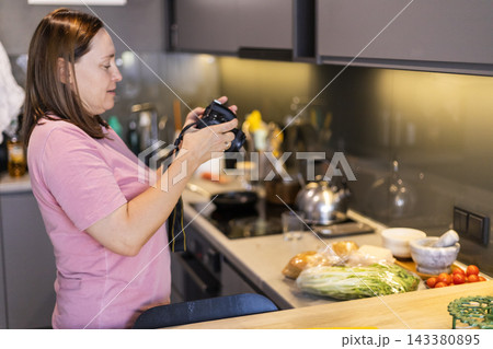 Woman photographing food ingredients in modern kitchen with DSLR Woman photographing food ingredients in modern kitchen with DSLR 143380895