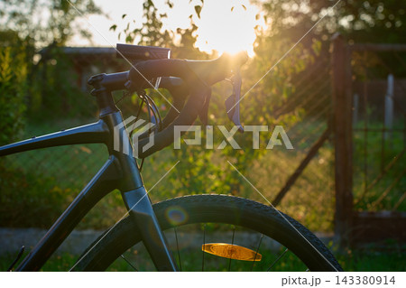 Bicycle handlebars and front wheel at sunset Bicycle handlebars and front wheel at sunset 143380914