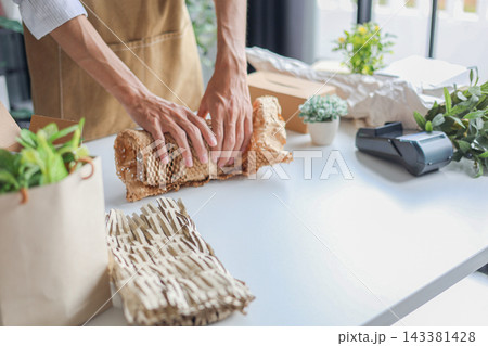 A small business, a florist or a gift shop worker preparing, wrapping, packing a customer's order. 143381428