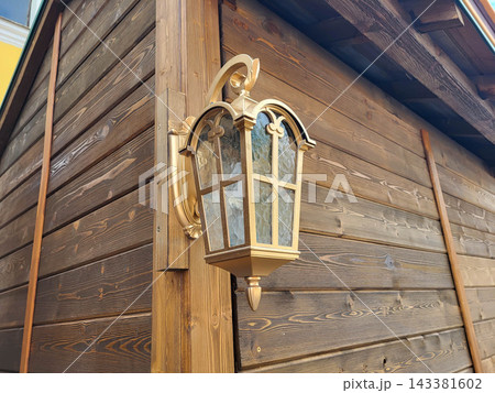 A gilded antique style lantern hangs on the wooden wall A gilded antique style lantern hangs on the wooden wall 143381602