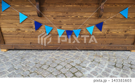 Blue triangular flags are hanging on the wooden background of the wall 143381603