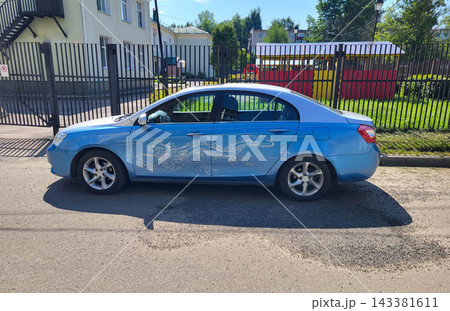 On a summer day, a car is standing in the yard. A white dragon is painted on the side of the blue car. On a summer day, a car is standing in the yard. A white dragon is painted on the side of the blue car. 143381611