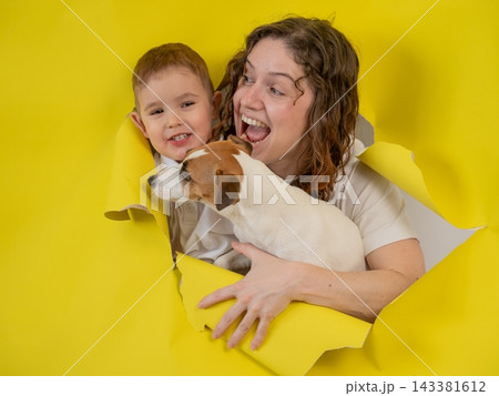 Caucasian little boy, his mother and Jack Russell Terrier dog tearing yellow paper background. Caucasian little boy, his mother and Jack Russell Terrier dog tearing yellow paper background. 143381612