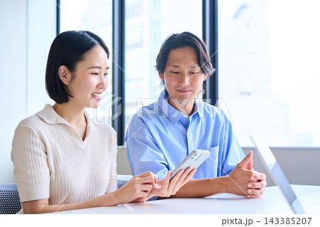明るいオフィスで資産形成やライフプランの相談をする若い夫婦 143385207