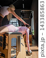 Women doing Swan exercise on Pilates Chair for the chest and back muscles, focusing on flexibility, strength, and control with determination 143385863