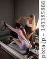 Woman doing pilates exercises for hands and back using the Reformer straps. Reformer pilates studio machine for fitness workouts 143385866