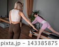 Young caucasian women exercising Scooter on pilates reformers for the hips and glutes in a bright studio. Her workout focuses on strength and flexibility 143385875