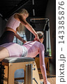 Women doing Swan exercise on Pilates Chair for the chest and back muscles, focusing on flexibility, strength, and control with determination 143385876