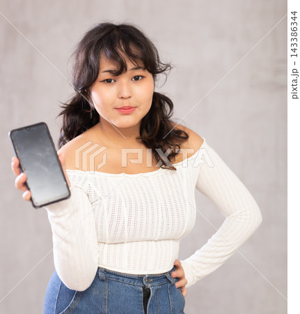 Smiling young girl holding mobile phone Smiling young girl holding mobile phone 143386344