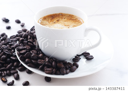 エスプレッソに牛乳をたっぷり入れたコーヒー、カフェ・ラッテと、深煎りしたコーヒー豆 エスプレッソに牛乳をたっぷり入れたコーヒー、カフェ・ラッテと、深煎りしたコーヒー豆 143387411