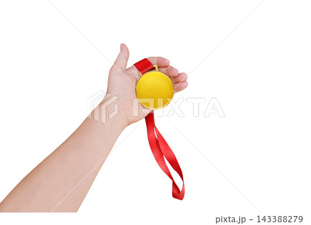 Close up of a hand holding a blank gold medal with red ribbon isolated on white background. Close up of a hand holding a blank gold medal with red ribbon isolated on white background. 143388279