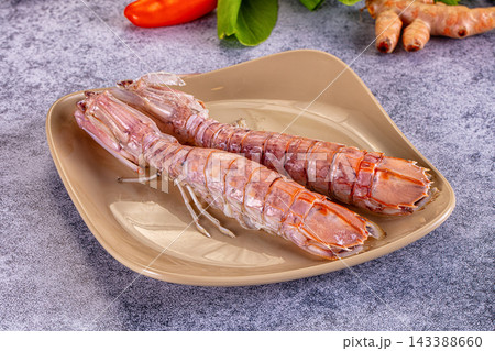 Beige ceramic plate with raw pink scampi crustacean seafood 143388660