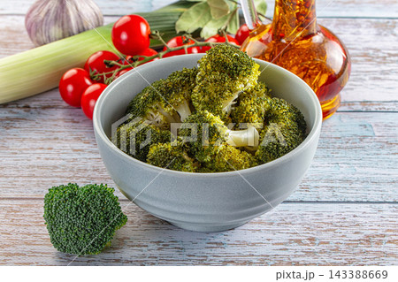 Steamed green broccoli florets in grey ceramic bowl with cherry tomatoes, leek and garlic on wooden table, healthy vegetable side dish Steamed green broccoli florets in grey ceramic bowl with cherry tomatoes, leek and garlic on wooden table, healthy vegetable side dish 143388669