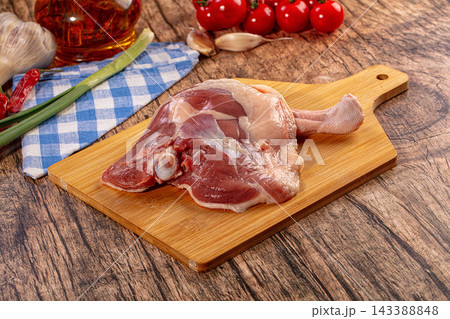 Raw duck leg on wooden cutting board with fresh vegetables and spices. Uncooked poultry meat preparation for healthy cooking 143388848