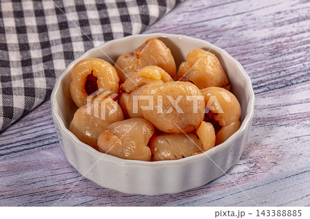 Dried longan fruit in white ceramic bowl on rustic wooden surface with checkered cloth background, food ingredient Dried longan fruit in white ceramic bowl on rustic wooden surface with checkered cloth background, food ingredient 143388885