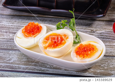 White ceramic plate, boiled egg with red caviar, gourmet appetizer snack White ceramic plate, boiled egg with red caviar, gourmet appetizer snack 143389029