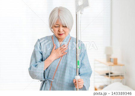 手術や病気への不安を抱え胸に手を当てるシニア女性。治療や今後を心配する入院患者の高齢者 143389346