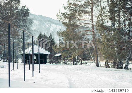 cozy log cabin in snowy countryside setting surrounded by evergreen trees and mountains. The scene evokes a sense of tranquility and mindfulness. 143389719