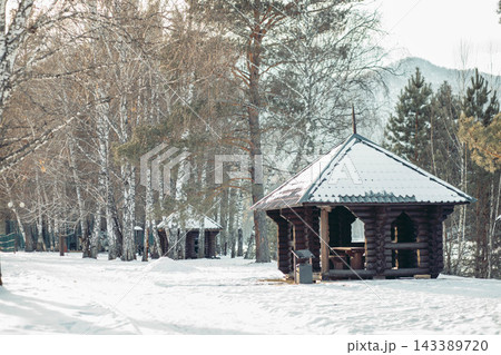 cozy log cabin in a snowy countryside setting surrounded by evergreen trees and mountains. The scene evokes a sense of tranquility and mindfulness. 143389720