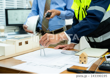 Two  colleagues discussing data working and tablet, laptop with on on architectural project at construction site at desk 143390195