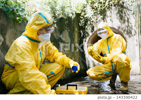 Biologists in protective hazmat suits collect water samples from a drainage pipe Biologists in protective hazmat suits collect water samples from a drainage pipe 143390422