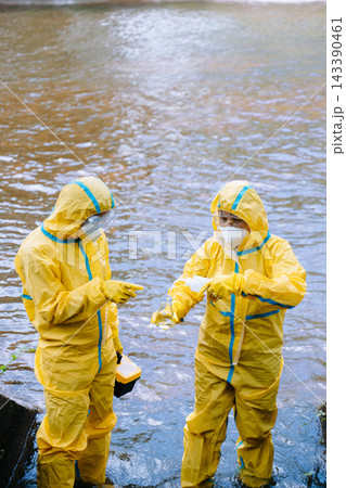 Environmental scientists in yellow protective suits analyze polluted water samples in glass flasks Environmental scientists in yellow protective suits analyze polluted water samples in glass flasks 143390461